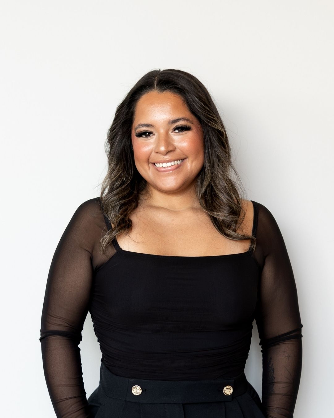 Woman wearing a black dress with sheer sleeves against a white background