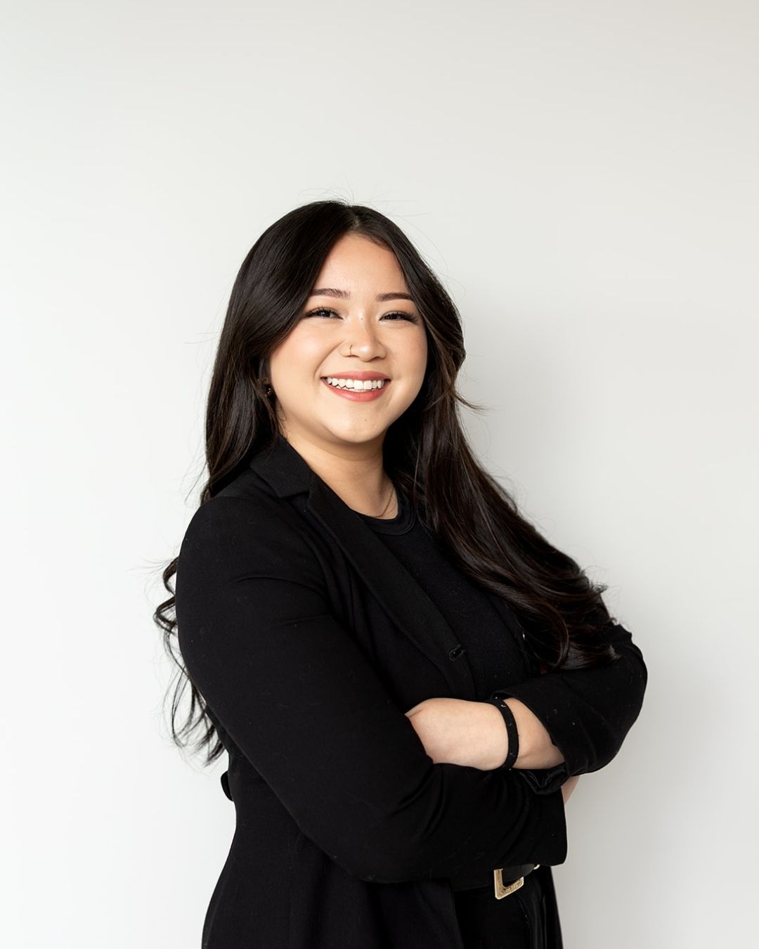 Woman in a black coat standing against a white background