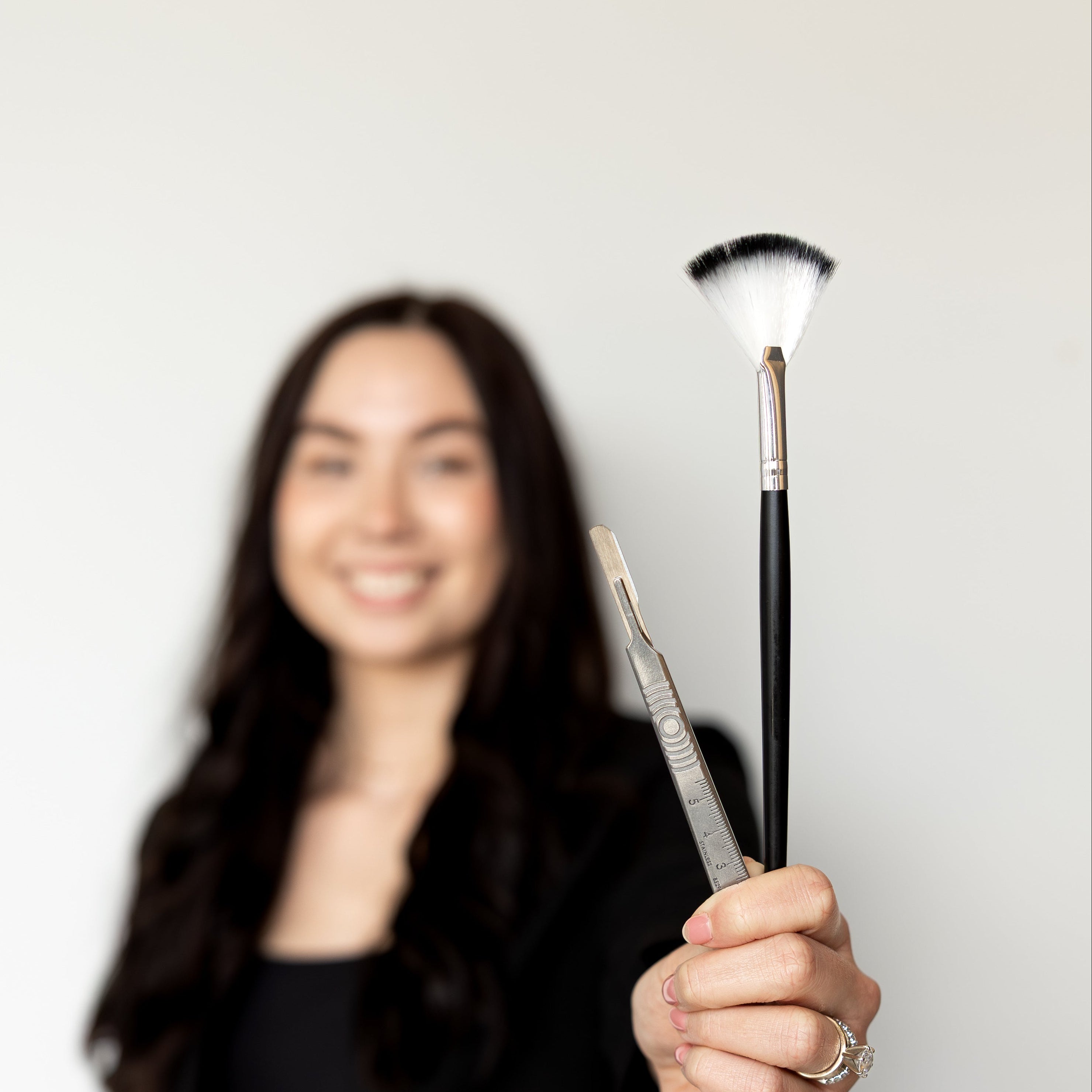 Woman holding a makeup brush against a white background