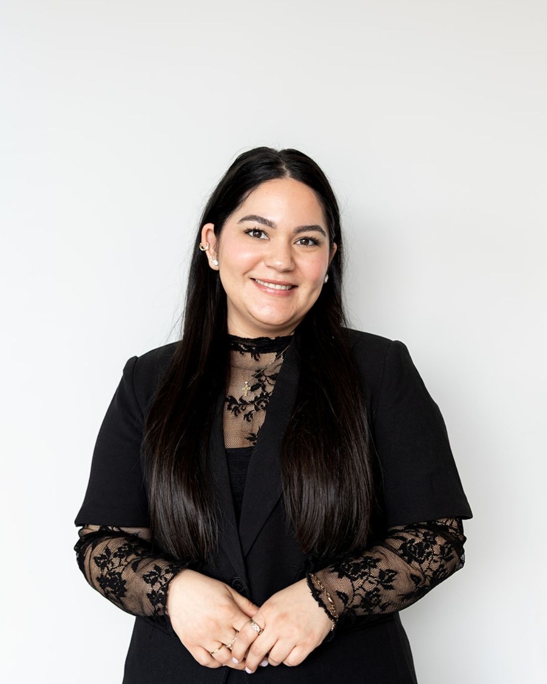 Woman wearing a black outfit with lace details against a white background