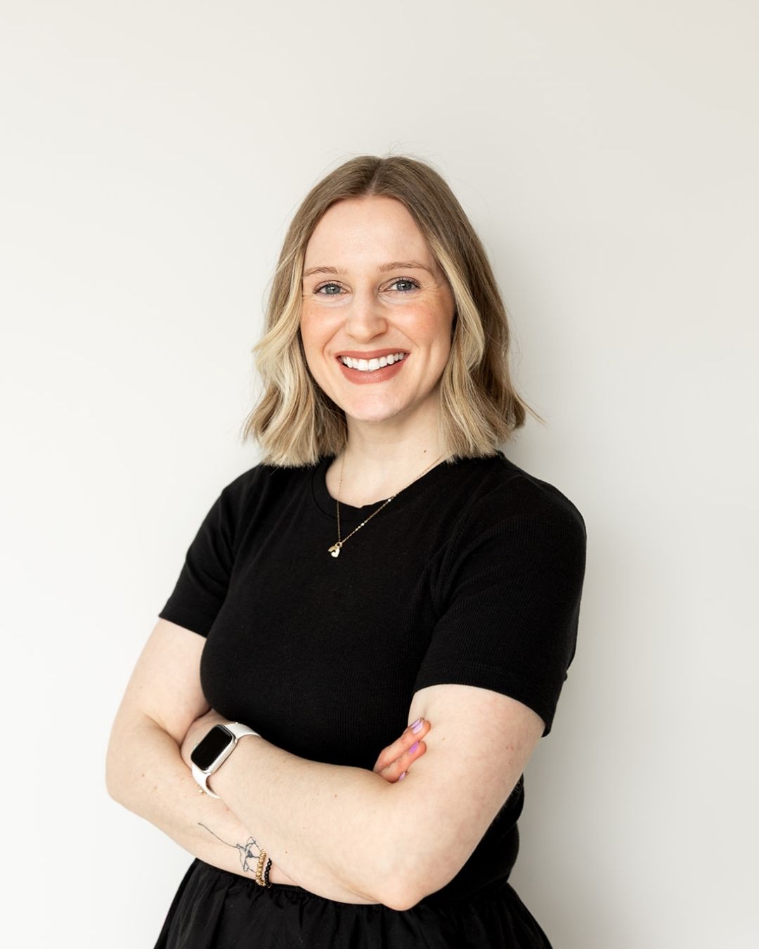 Woman wearing a black shirt with arms crossed against a white background