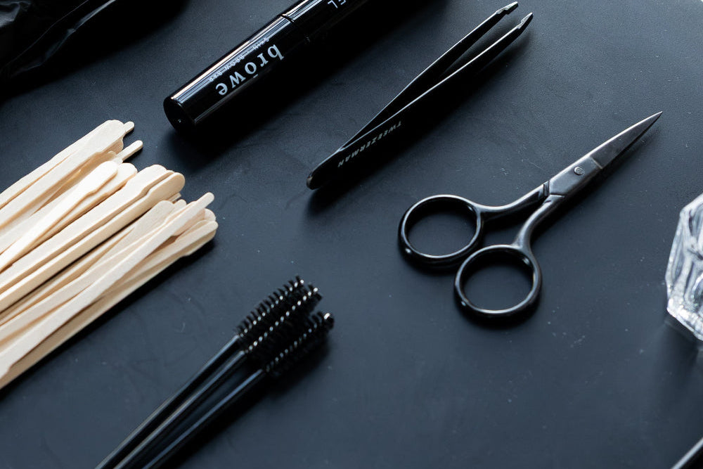 Black grooming tools including scissors, comb, and hair products on a dark surface.