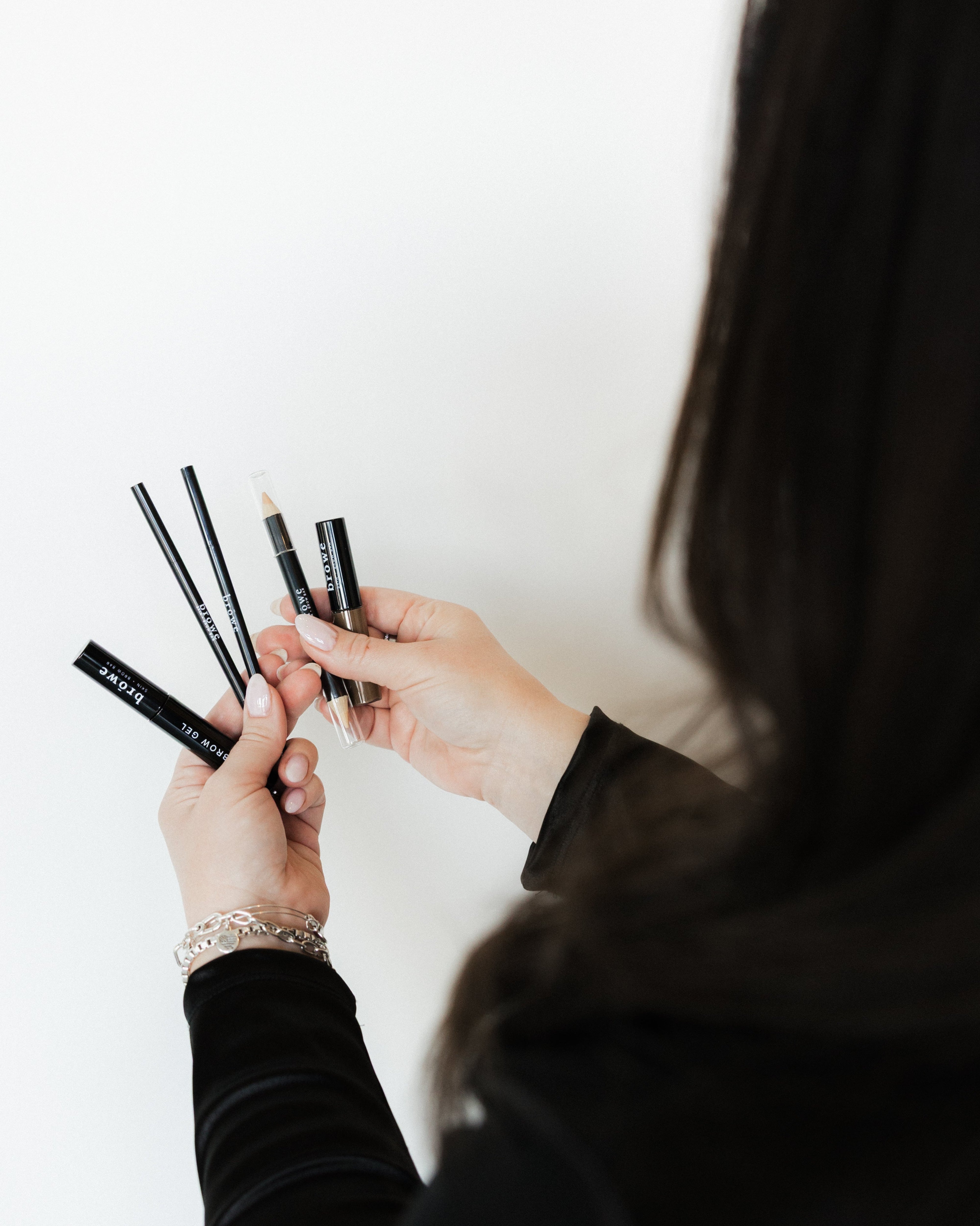 Person holding makeup brushes against a white background