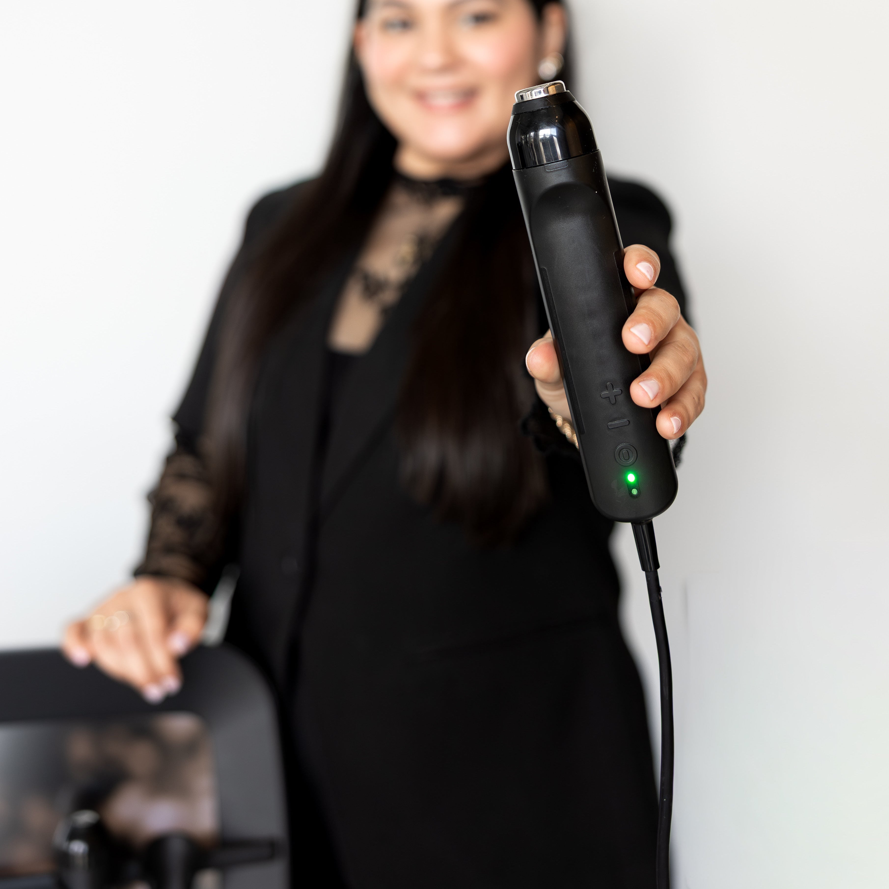 Woman holding a black hair removal device with a blurred background
