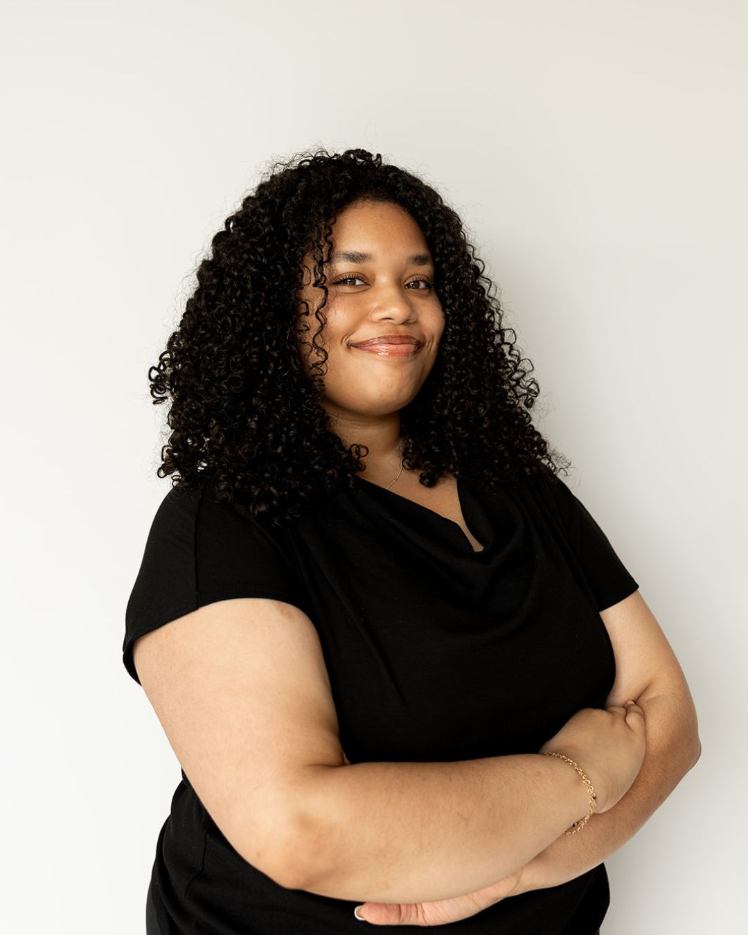 Woman with curly hair wearing a black top against a white background