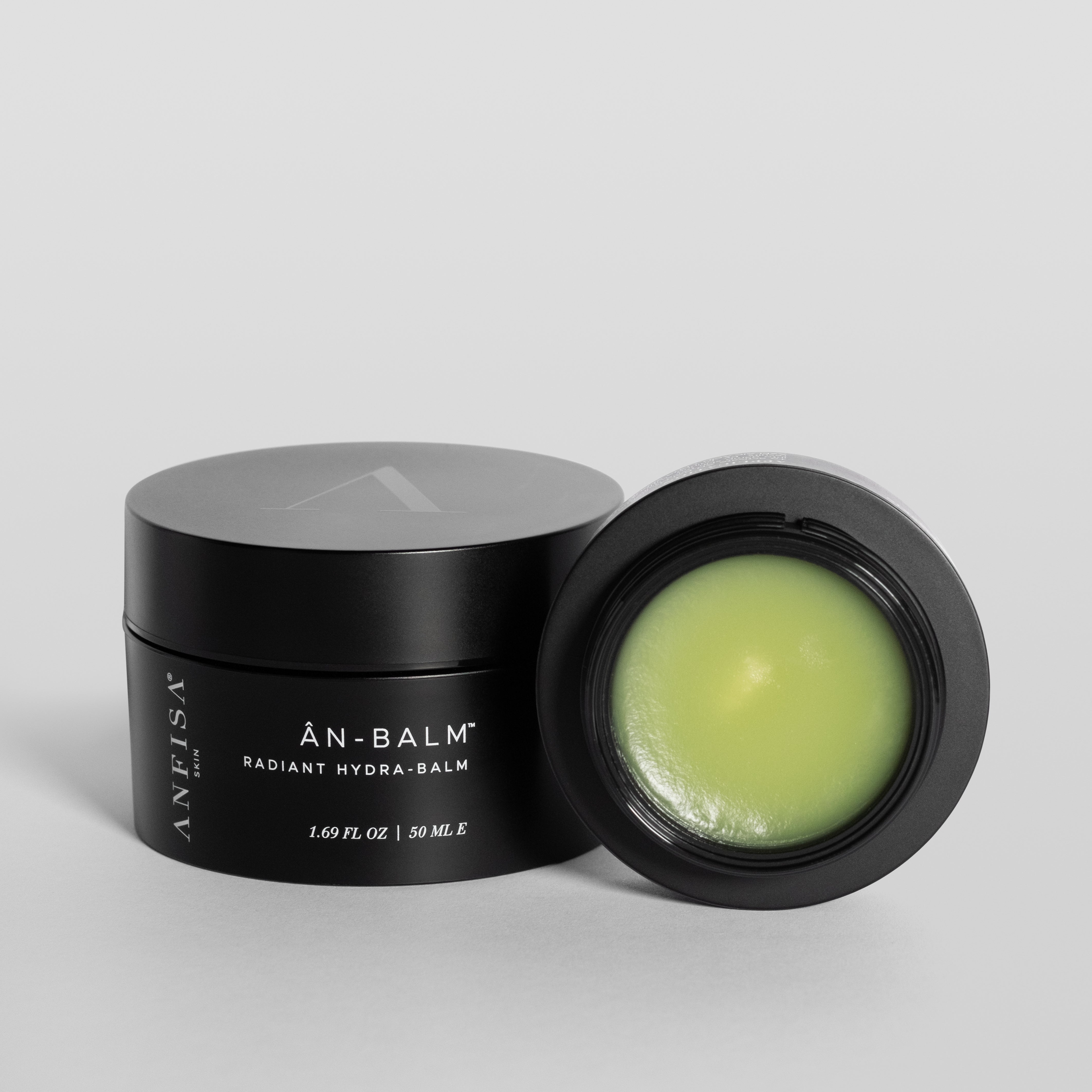 Black jar of 'An-Balm' with green balm on a gray background