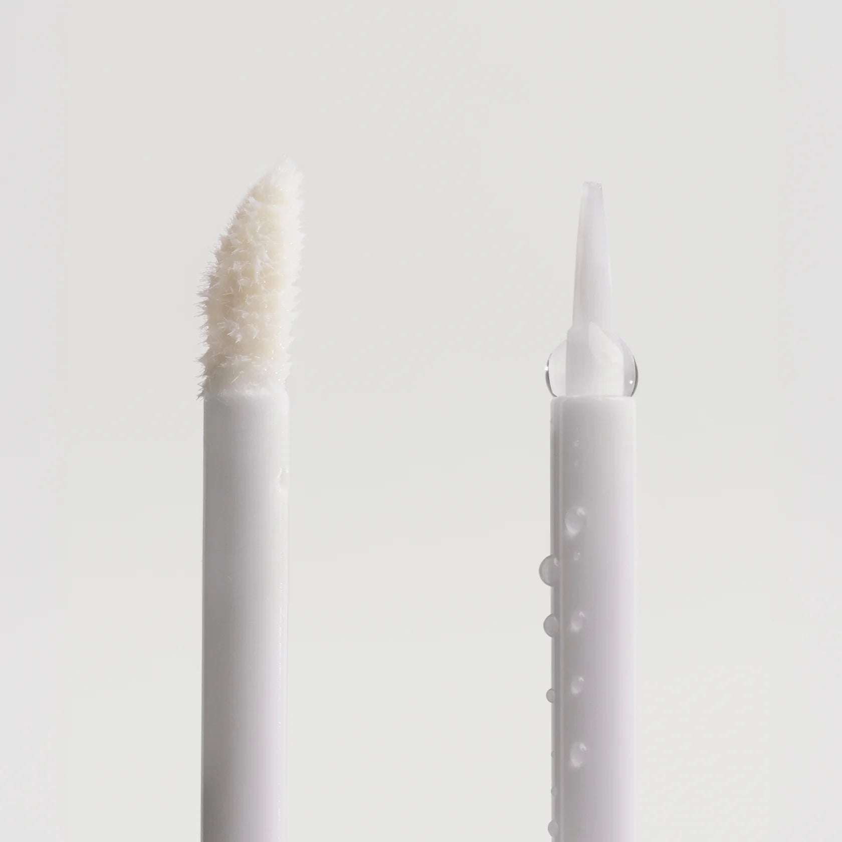 Two white candles with textured finishes on a light gray background