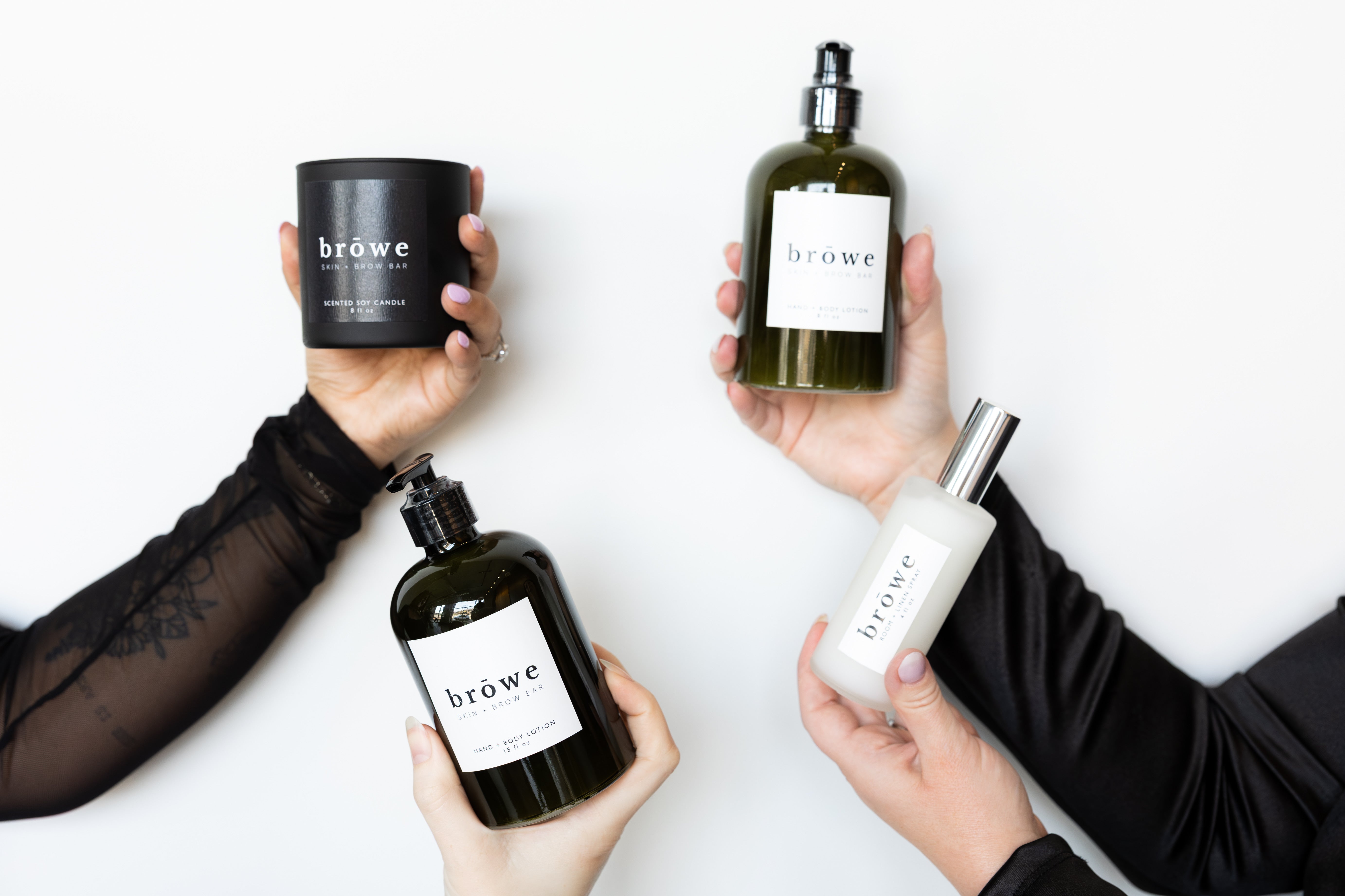 Four bottles of 'browe' products held by hands against a white background