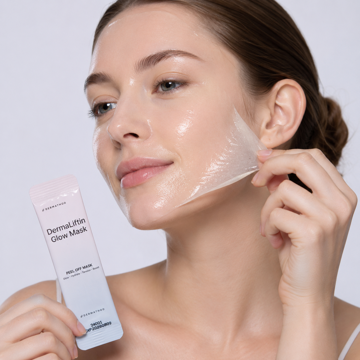 Woman applying a DermaLift Glow Mask to her face with a white background