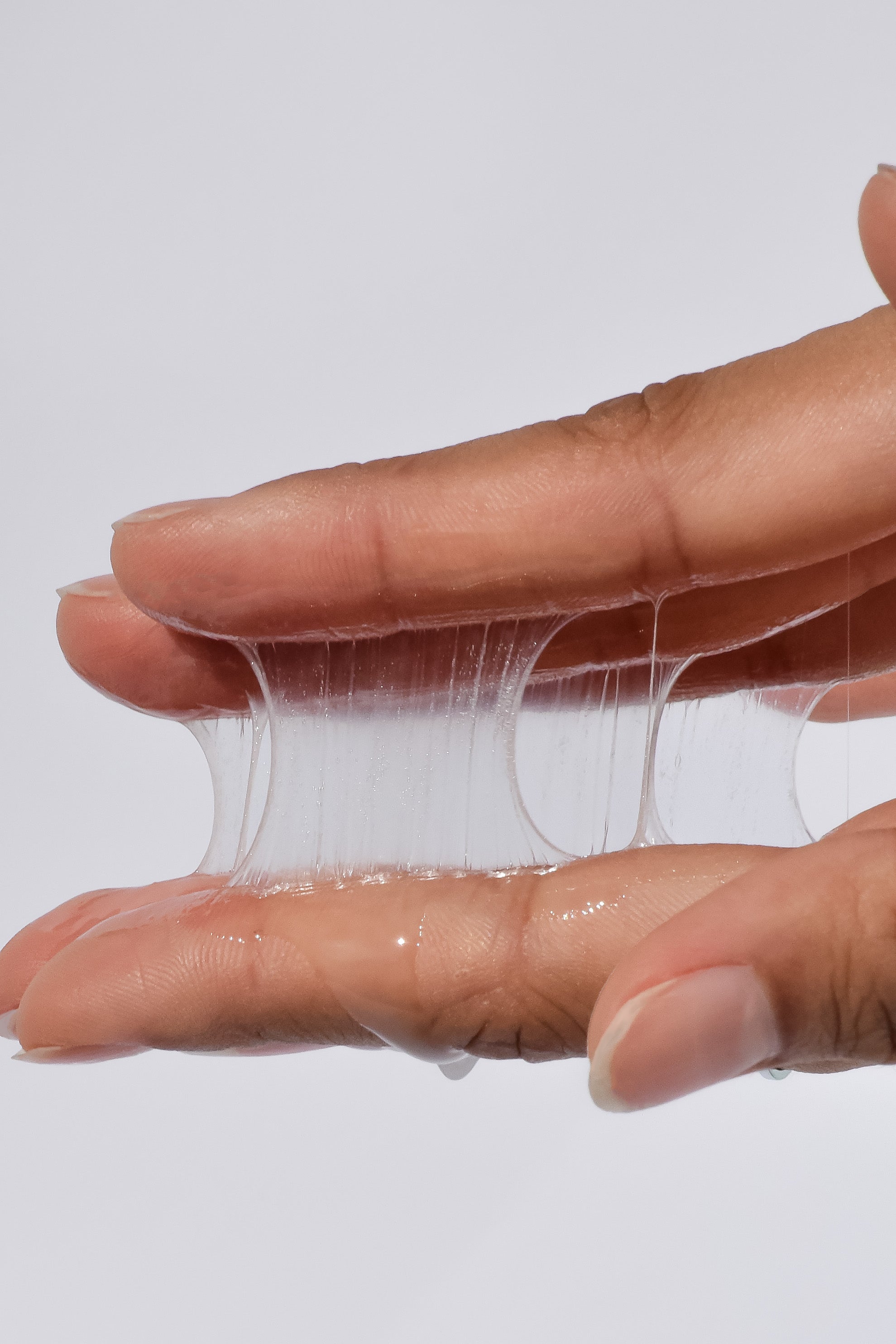 Hand stretching clear elastic band against a light gray background