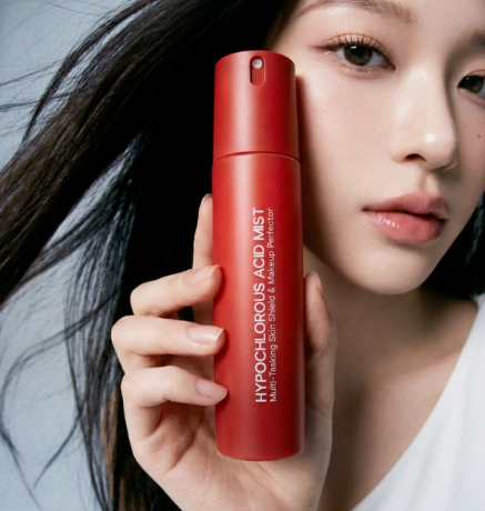 Red skincare product held by a person with a neutral background